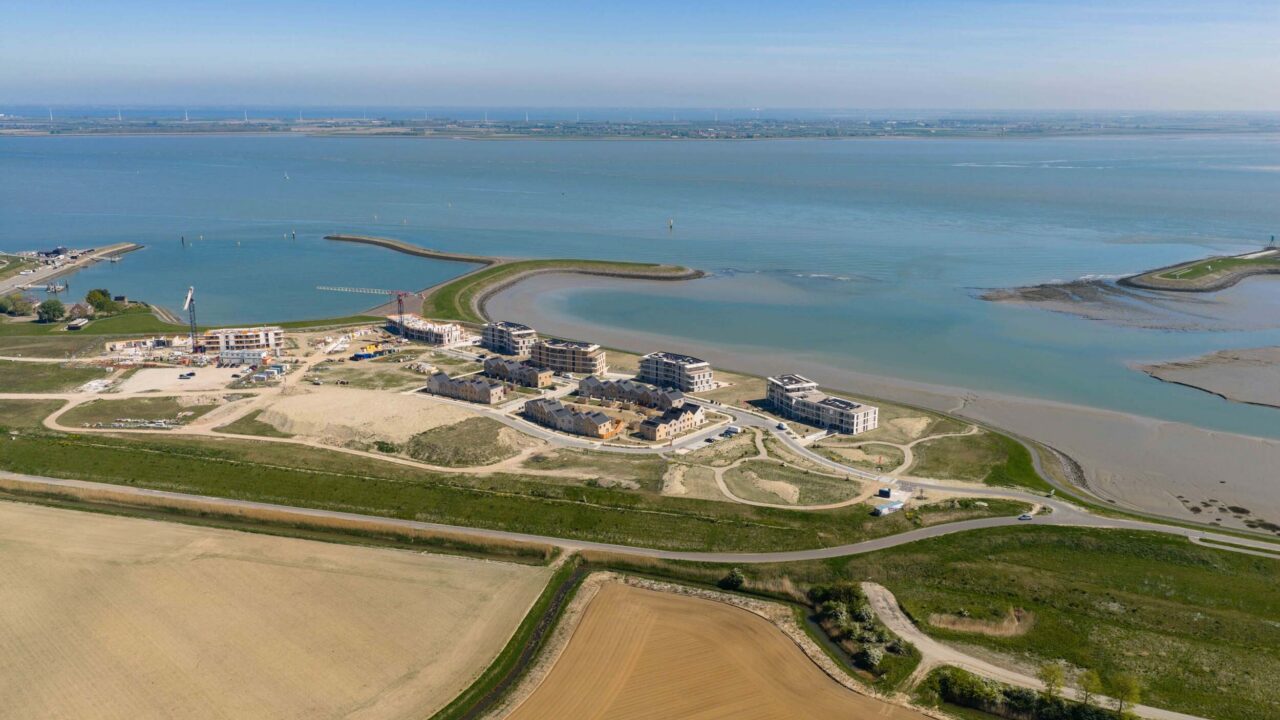 Luchtbeeld van Waterzande aan de Westerschelde, met woningen, groen en de dijk
